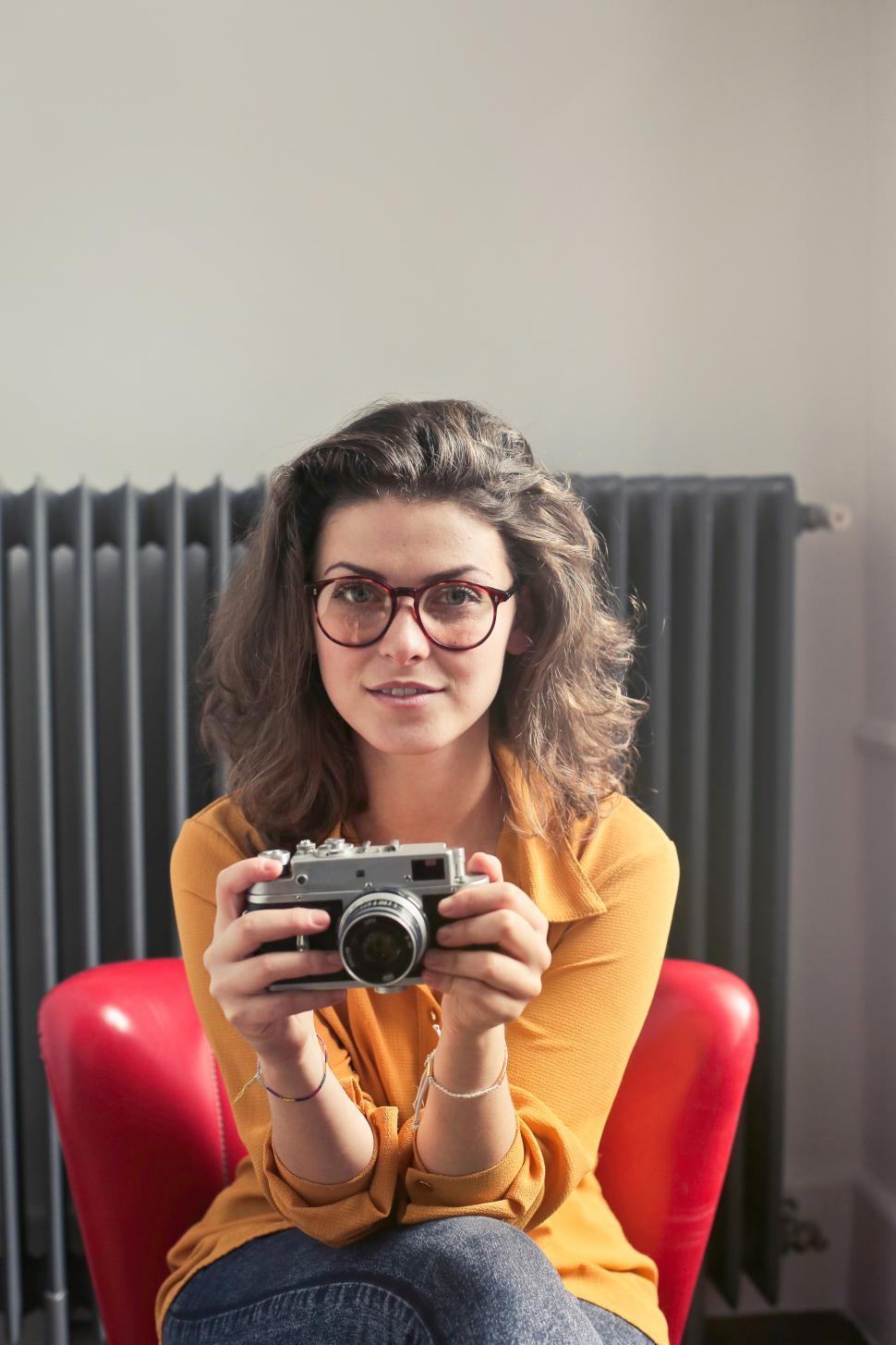Free Image of Young Woman Wearing Yellow Collared Shirt With Spectacles Holdin 