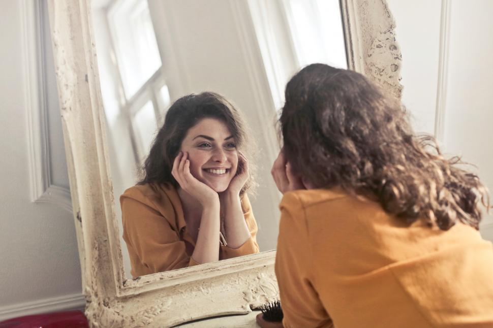 Free Image of Young woman looking herself reflection in mirror at home 