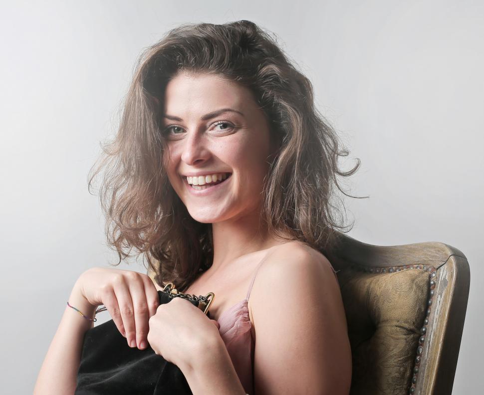 Free Image of Young Woman Holding Bag While Sitting On Chair 