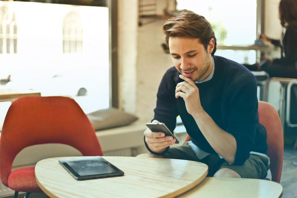 Free Image of Young Man In Black Sweater Using His Smartphone While Sitting In 