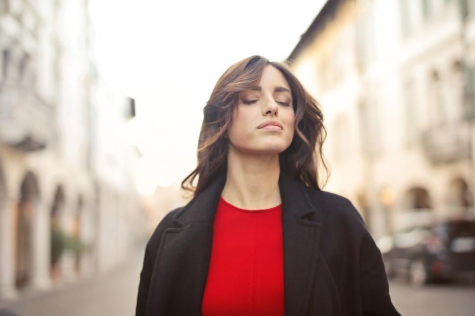 Free Image of Closed Eyes Woman In Black Blazer And Red Shirt Walking On Stree 