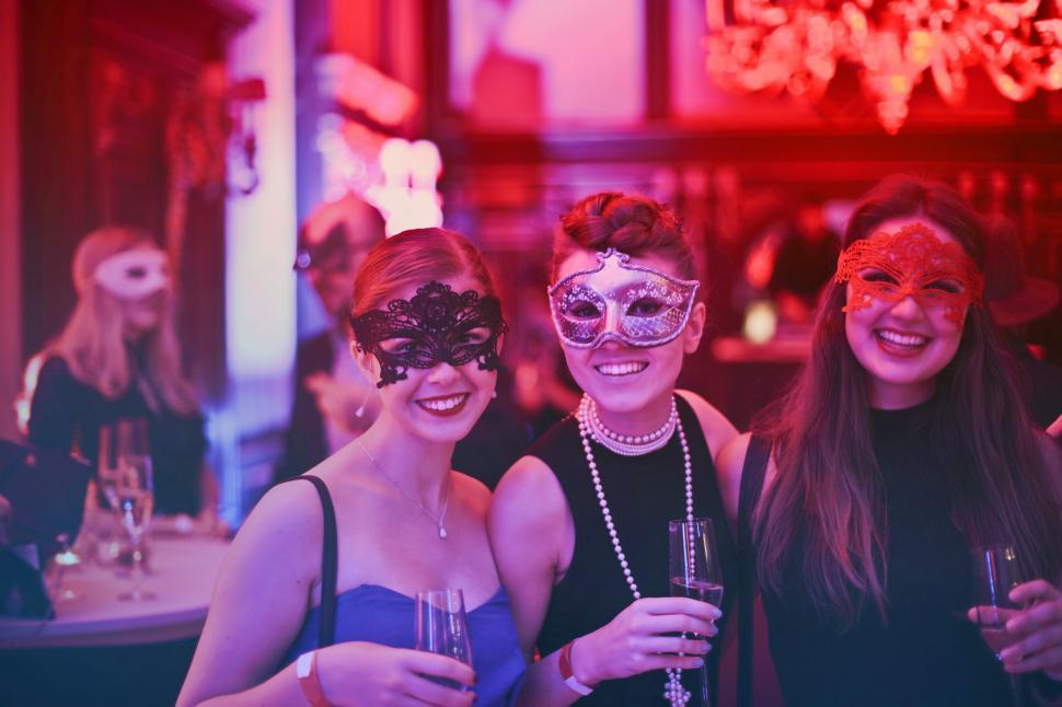 Free Image of Three Women In Masks Holding Wine Glasses In Nightclub 