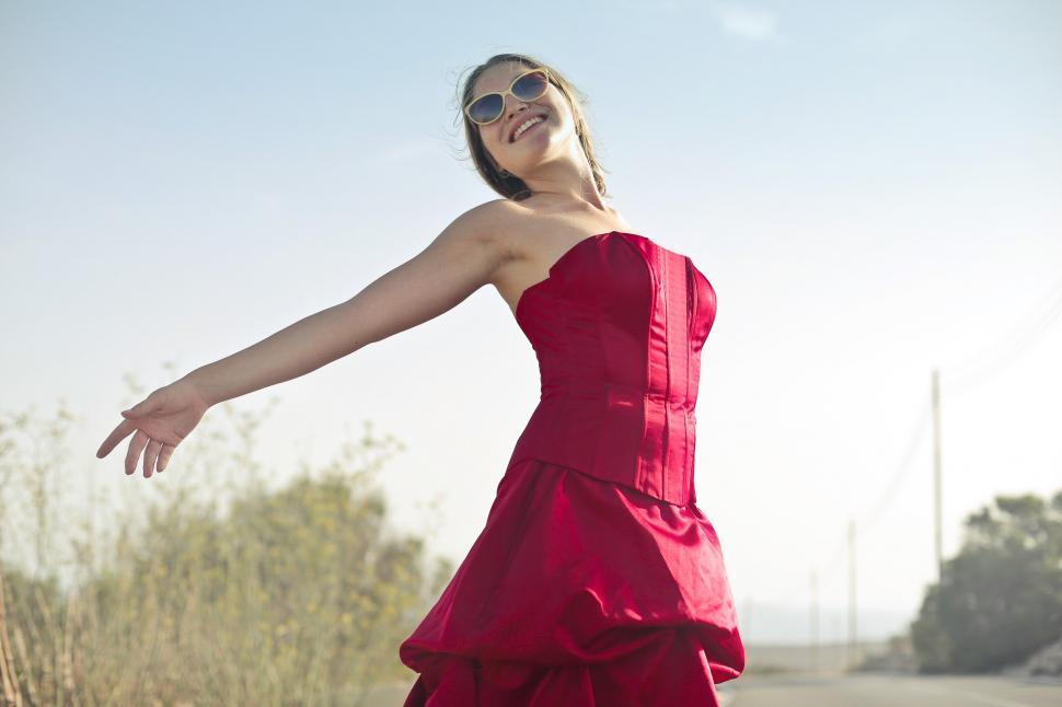 Free Image of Young Adult Woman In Red Party Gown Dress And Sunglasses During 