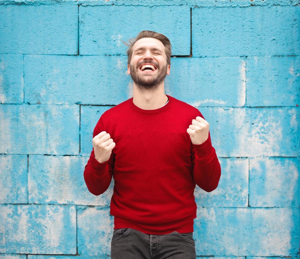 Free Image of A happy young caucasian man in red sweater standing against a br 