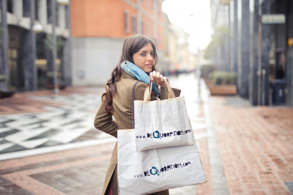 Free Image of A young blond woman holding shopping bags in her hand 