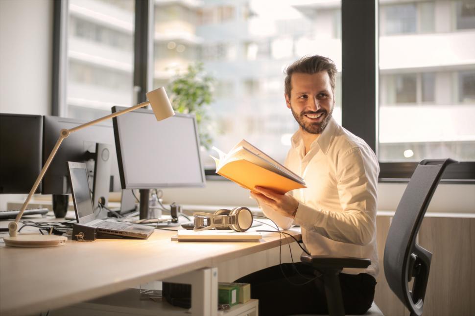 Free Image of A young man smiling while holding notebook in his hands 