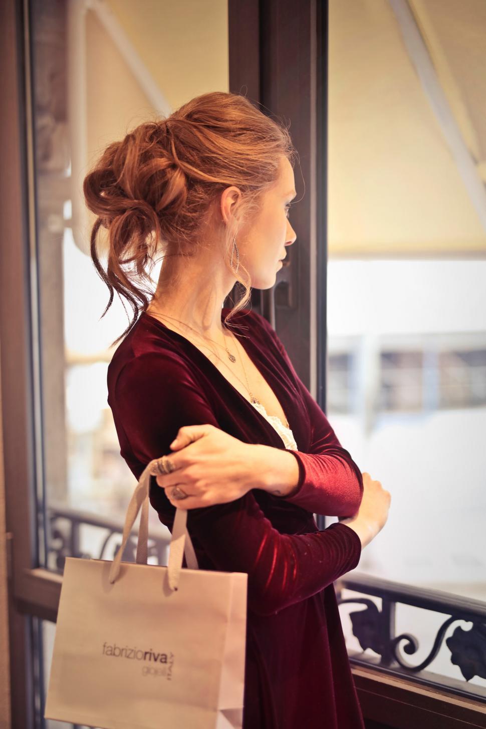 Free Image of A young blond woman with elegant hair bun holding a shopping bag 
