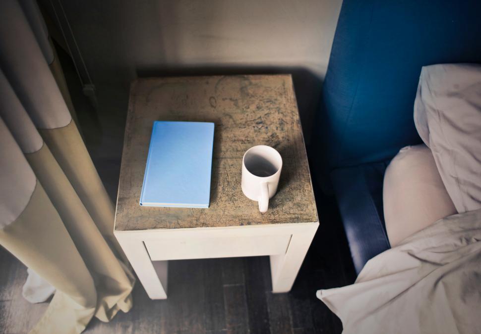 Free Image of A diary and a coffee mug on the bed side table 