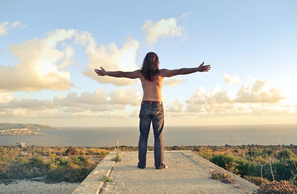 Free Image of A man standing on seashore  with his arms stertched 