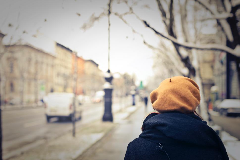 Free Image of A woman walking on the sidewalk on a winter day 