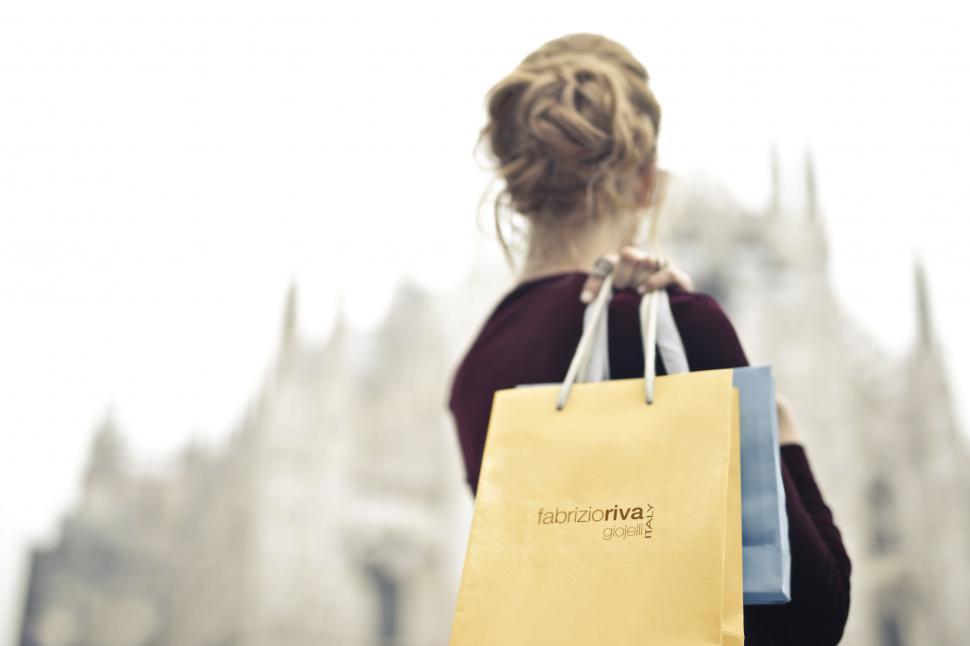 Free Image of A young blonde woman holding shopping bags in her hand on her sh 