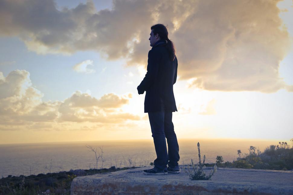 Free Image of A caucasian man with long hair standing on a seashore 