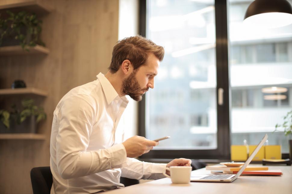 Free Image of A young bearded caucasian man looking at his laptop screen while 