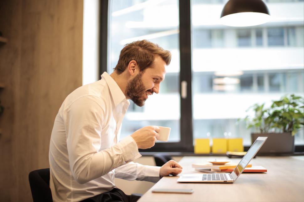 Free Image of A young bearded caucasian man looking at his laptop screen while 