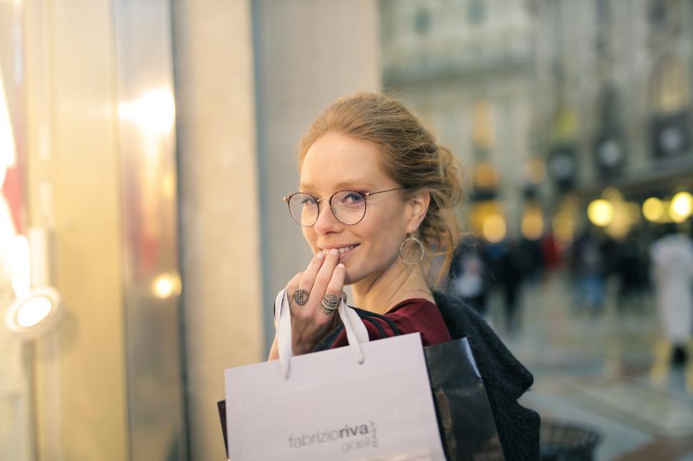 Free Image of A young blonde woman holding shopping bags in her hand looks ove 