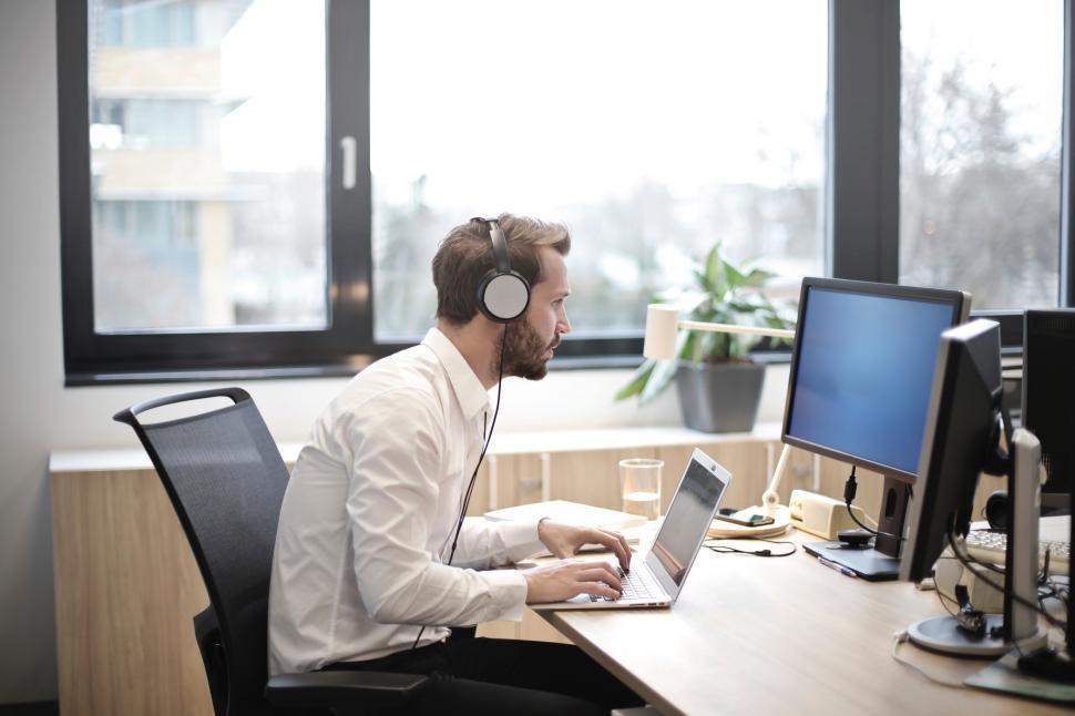 Free Image of A young caucasian man working on laptop while wearing headset 
