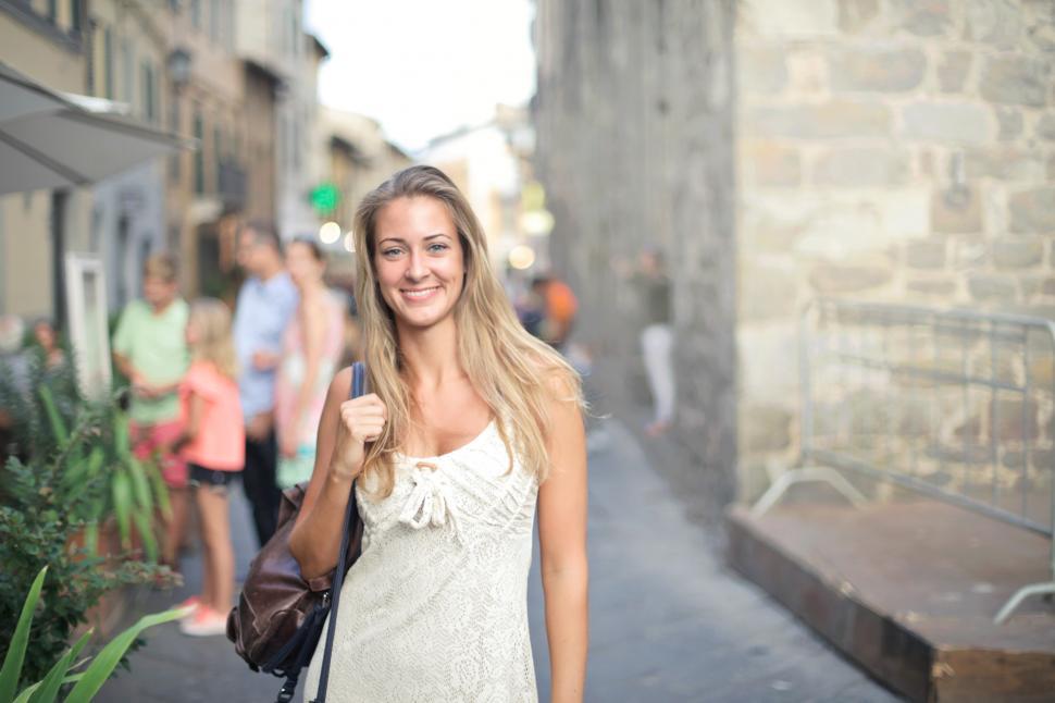 Free Image of A young blonde woman carrying a leather bag posing in the street 