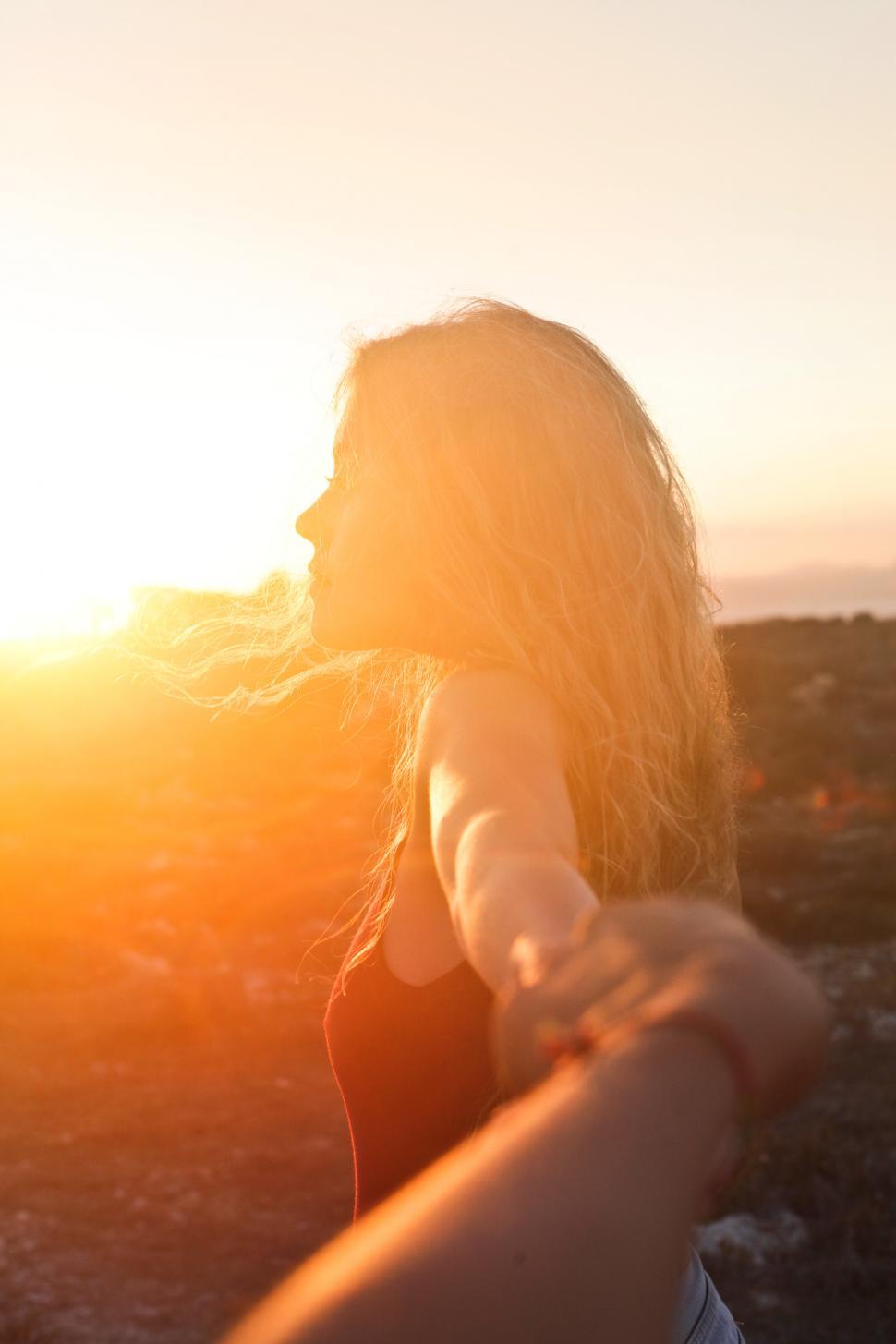 Free Image of A young blonde woman looking at the sunset 