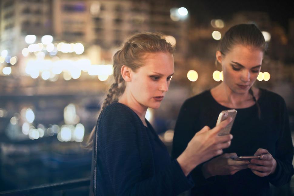 Free Image of Two young blonde women texting on their mobile phones 