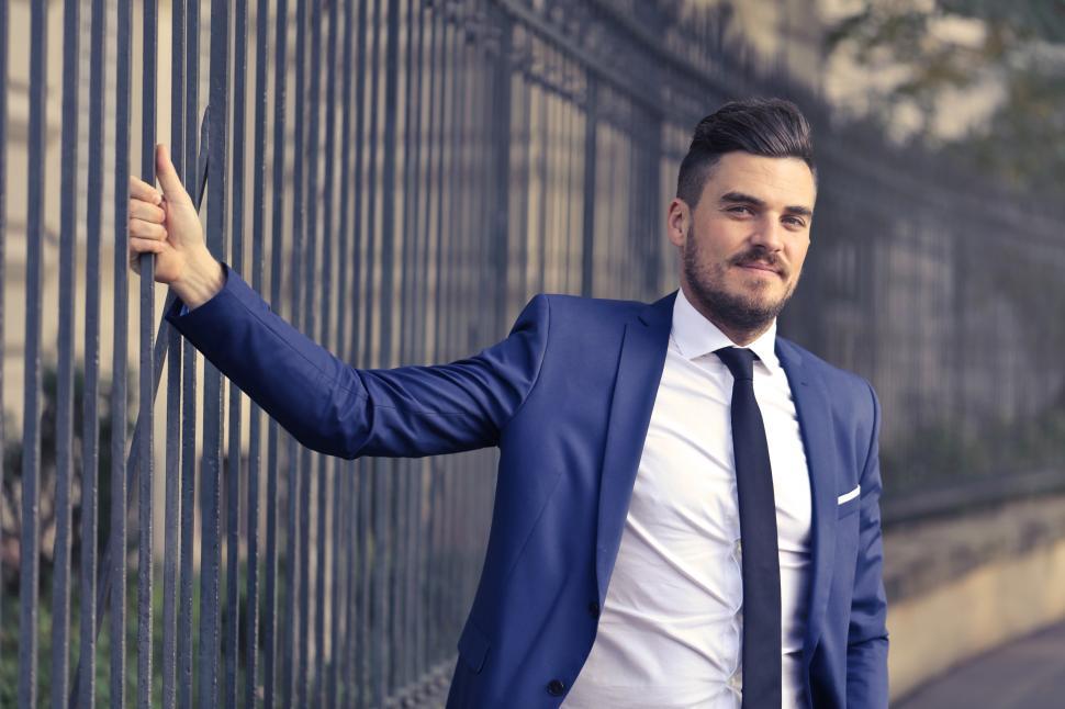 Free Image of A bearded caucasian man in formals standing against metal railin 