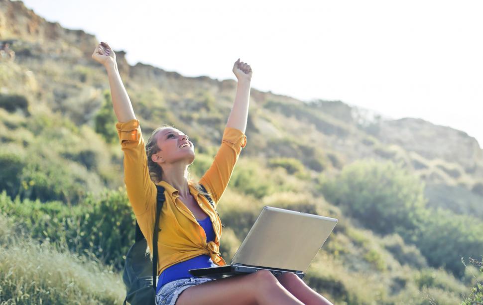 Free Image of A young blonde woman in yellow button-up shirt posing with a lat 