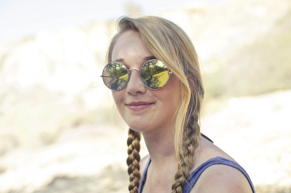 Free Image of A young blonde woman with sunglasses posing outdoors 