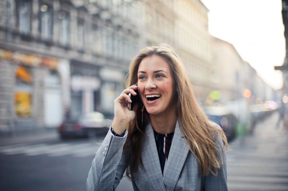 Free Image of A young blonde woman calling on her mobile phone in the street 