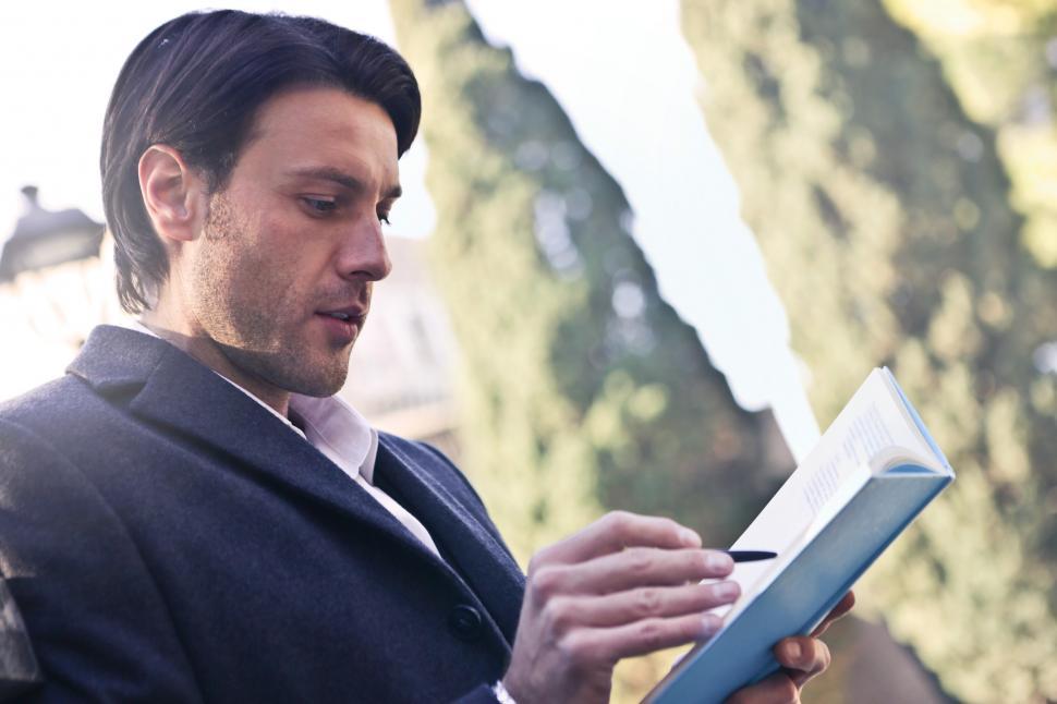 Free Image of A young caucasian man writing on a notebook in the park 