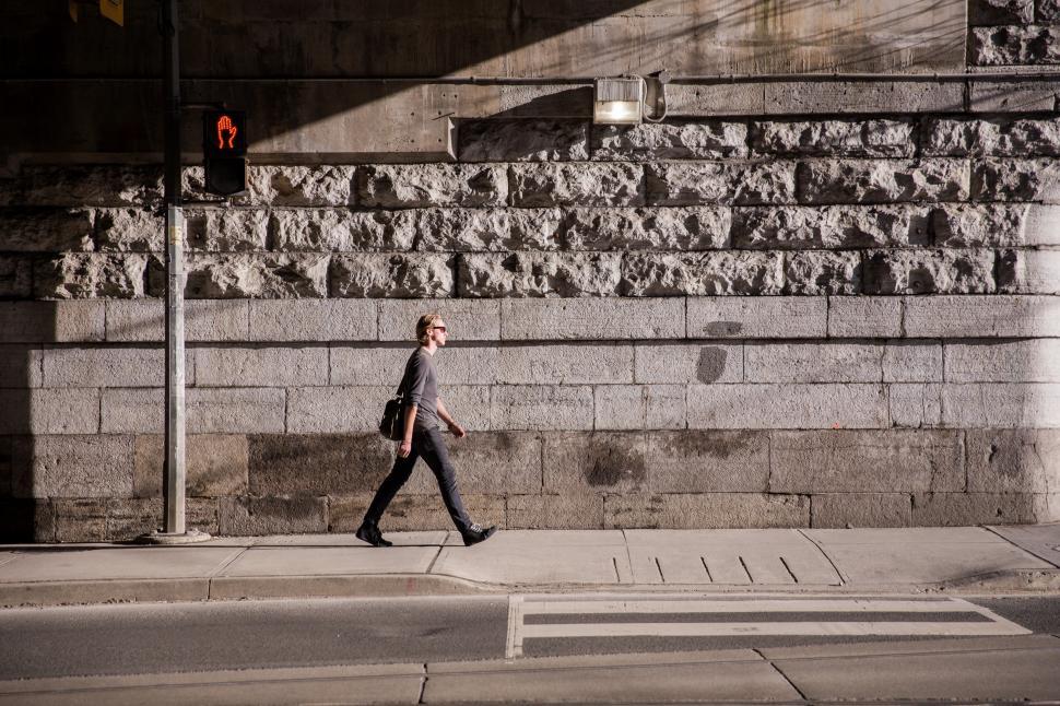 Free Image of A young caucasian man walking in urban sunlight 