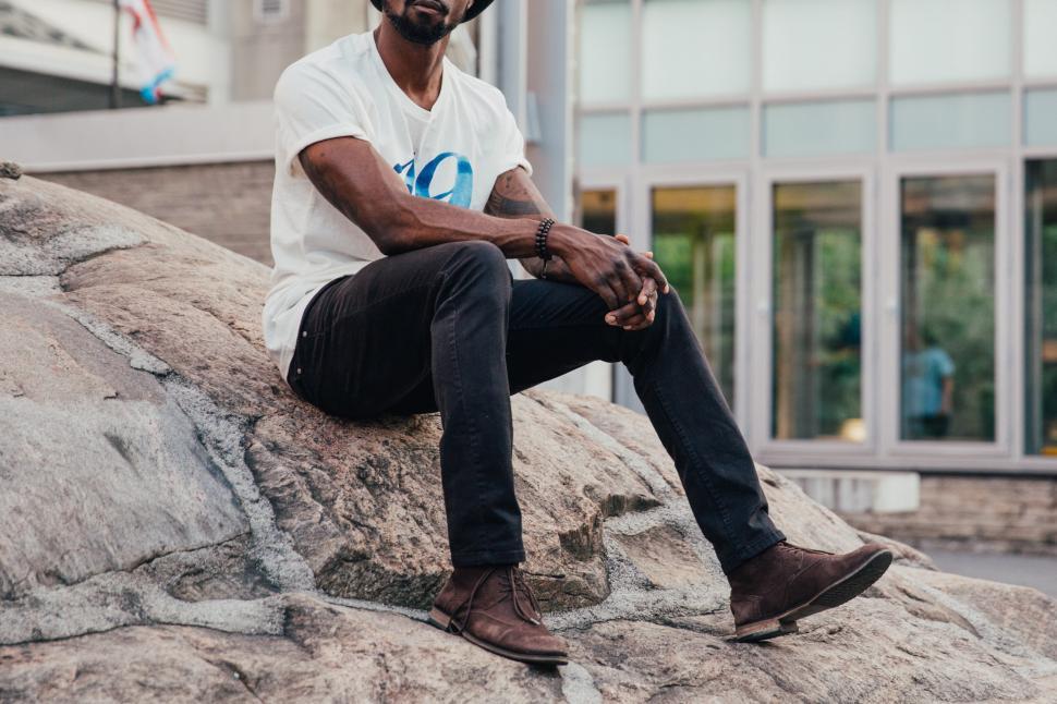 Free Image of A young man sits on a rock 