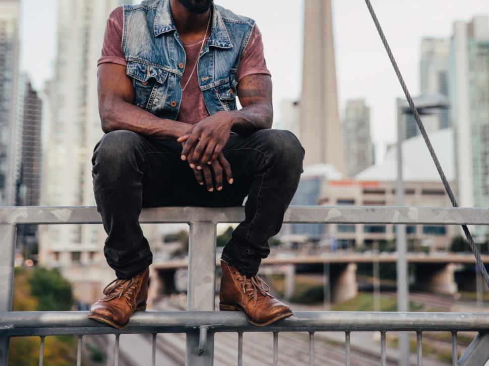Free Image of A young man sitting on a metal railing 