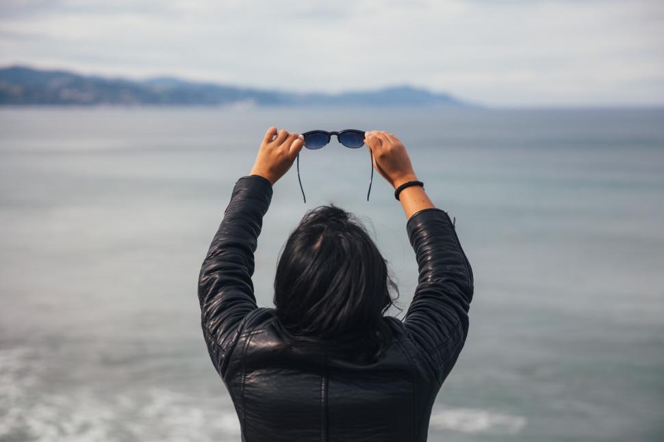 Free Image of A young woman holding sunglasses in her hands on the beach 