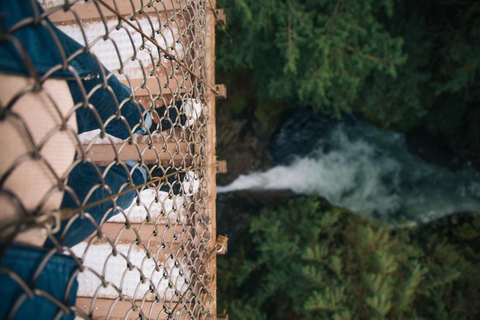 Free Image of Receding perspective view of legs on a bridge over water 