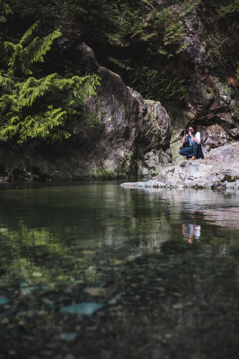 Free Image of A nature photographer near a clear water stream 