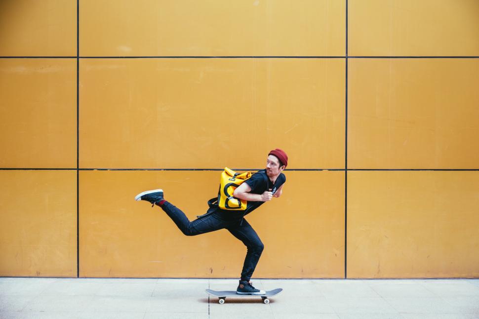 Free Image of A young caucasian skateboarder rides past a street wall 