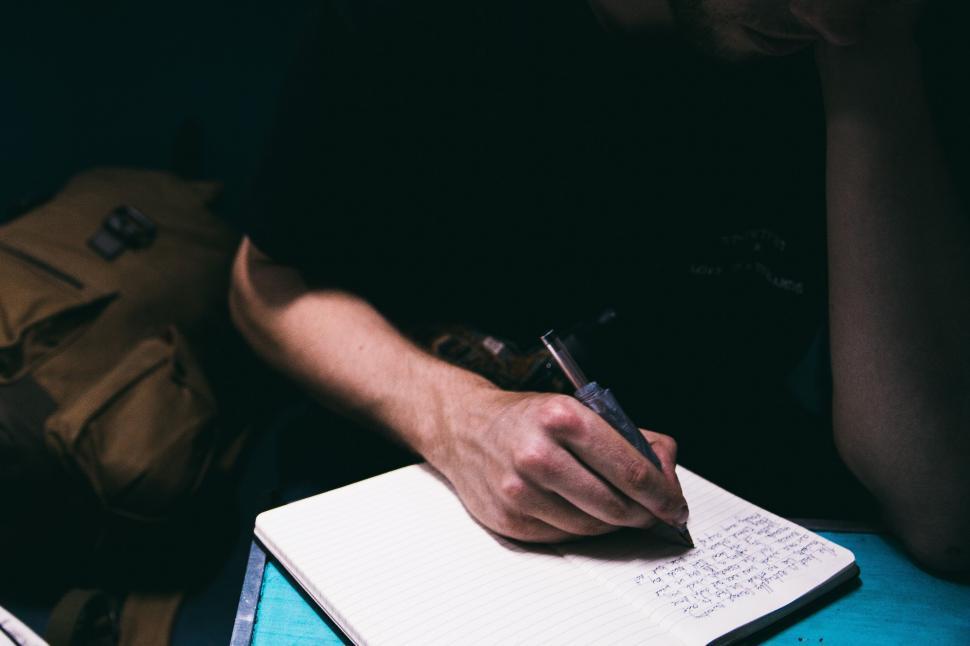 Free Image of A journalist writing on notepad 