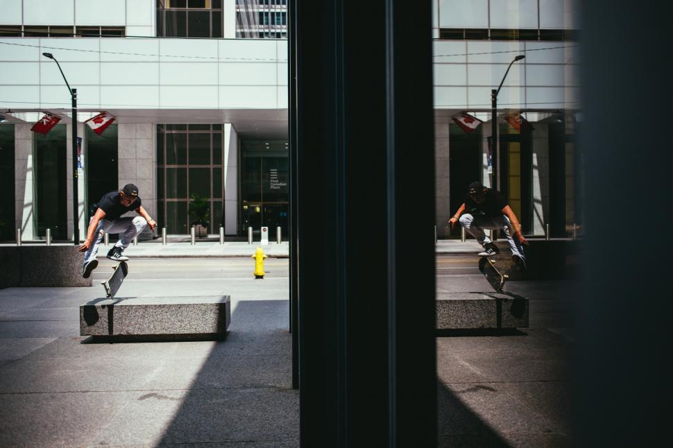 Free Image of A Caucasian skateboarder s kick flip with reflection on a buildi 