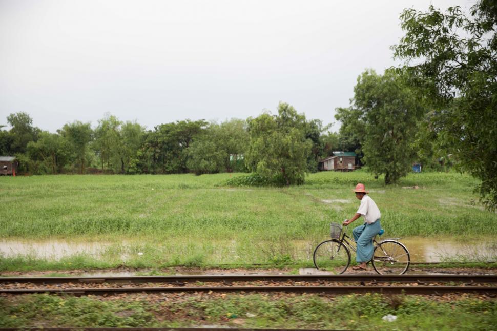 Free Image of A man riding a bicycle near train tracks 