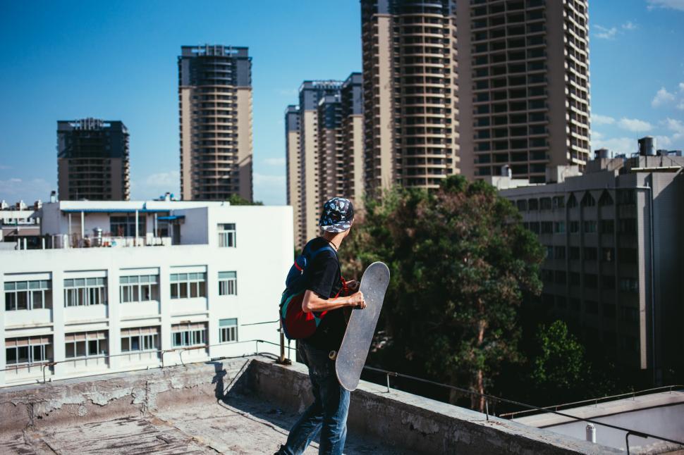 Free Image of A young caucasian skateboarder on a rooftop 