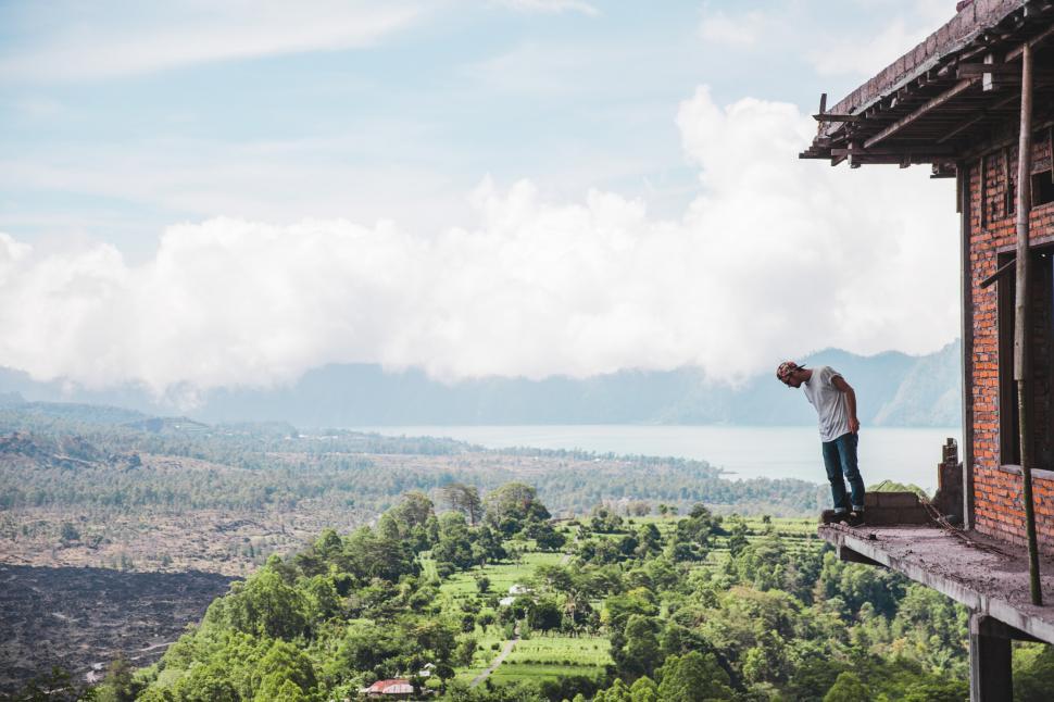 Free Image of A young Caucasian man standing on the edge of a balcony 