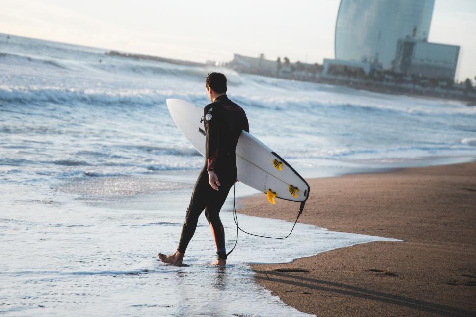 Free Image of A young Caucasian surfer carrying surfboard on the beach 