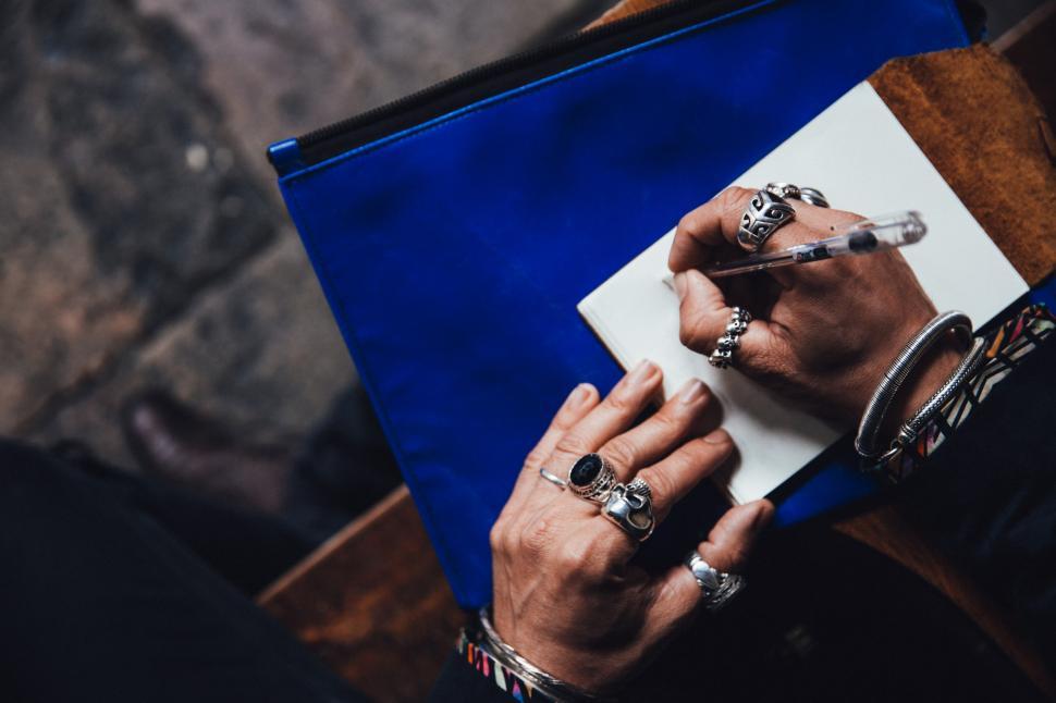 Free Image of Male hands wearing rings writing on paper 