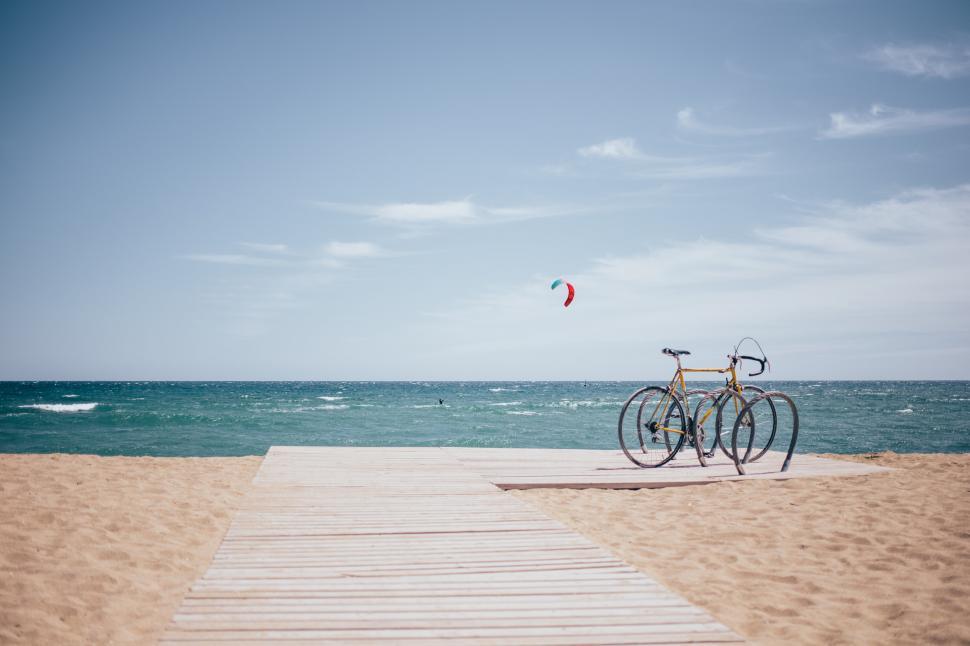 Free Image of Bicycle parked on a boardwalk on an active beach 