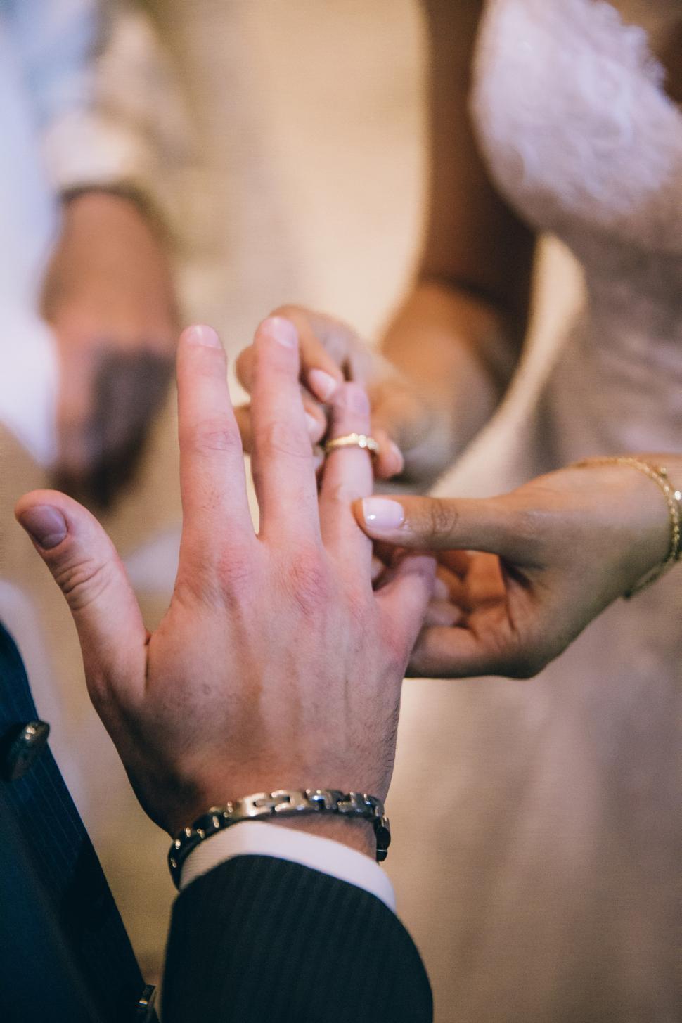 Free Image of Bride putting wedding ring on the groom s finger 