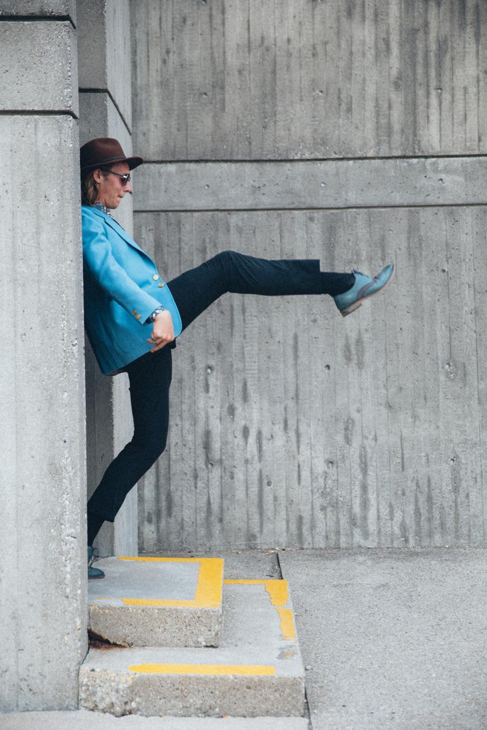 Free Image of A young aucasian man wearing turquoise blue jacket with one foot 