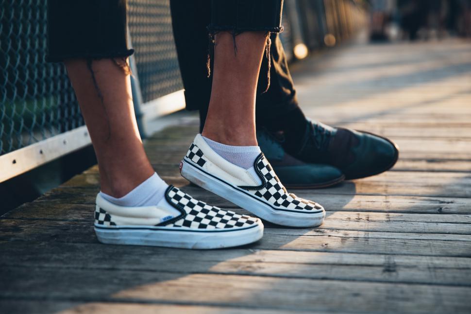 Free Image of A couple s feet with focus on woman s sneakers 