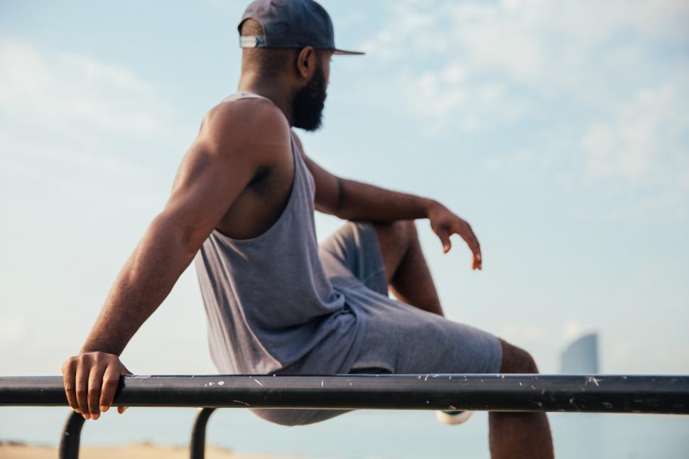 Free Image of A young African man relaxing on workout bars 