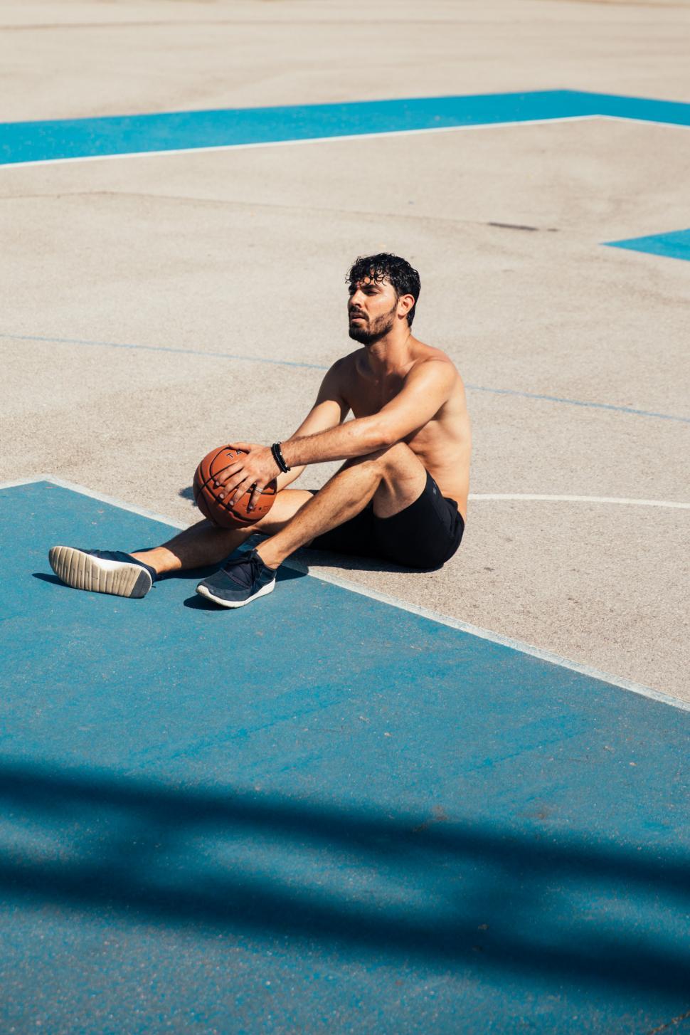 Free Image of A young player holding a basketball on the ground 
