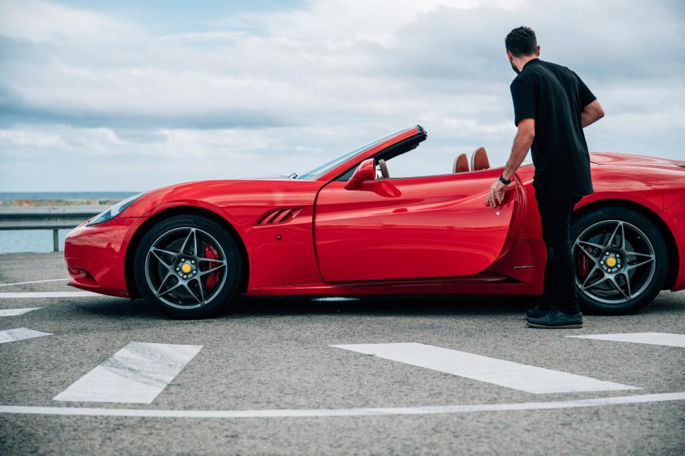 Free Image of A young man getting into a red convertible sports car 