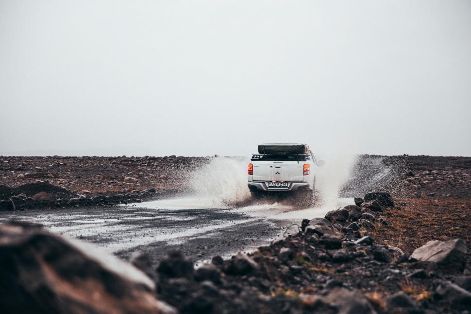 Free Image of Rear view of pick-up truck puddle splashing off-road 
